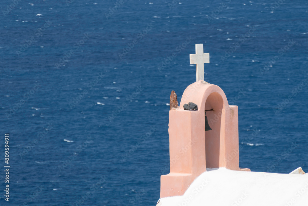 Santorini, Greece, May 5, 2024. Oia. Bell of a church with its white cross facing the sea Santorini, Greece, May 5, 2024. Oia. Bell of a church with its white cross facing the sea