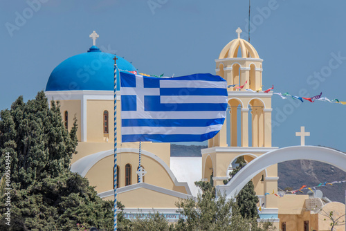 Santorini, Greece, May 4, 2024. Oia. Facade of the Orthodox church, Agios Giorgios, with a Greek flag