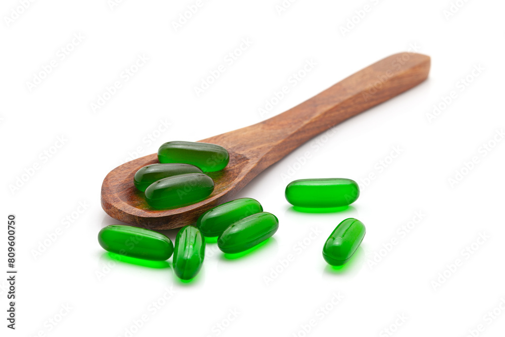 Health care concept. A wooden spoon filled with Vitamin E (Green) Medical Capsules. Isolated on a white background. Health care concept. A wooden spoon filled with Vitamin E (Green) Medical Capsules. Isolated on a white background.