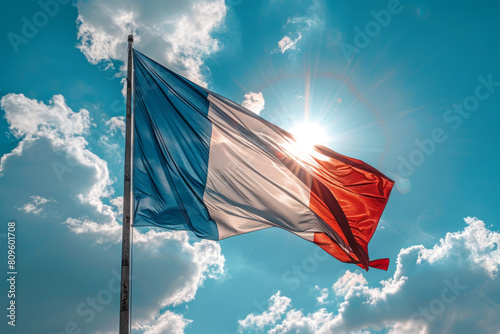 French flag waving against a sunny sky with clouds