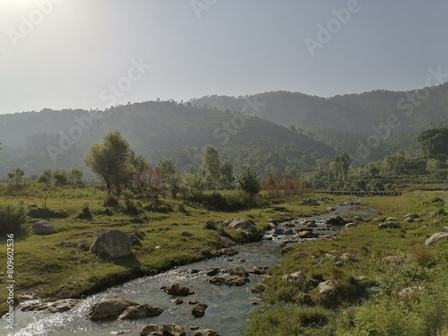 Obraz na płótnie A gentle brook babbles and winds its way through the heart of the lush green mou