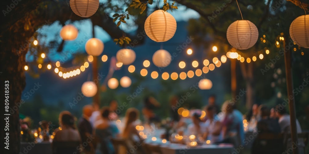 An evening outdoor party warmly illuminated by white hanging lanterns, offering a sense of celebration and intimacy