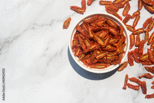 dried cherry tomatoes in white ceramic bowl on white marble table background.