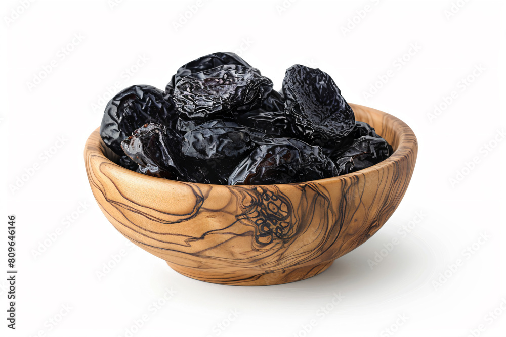 a wooden bowl filled with dried prunests a wooden bowl filled with dried prunests