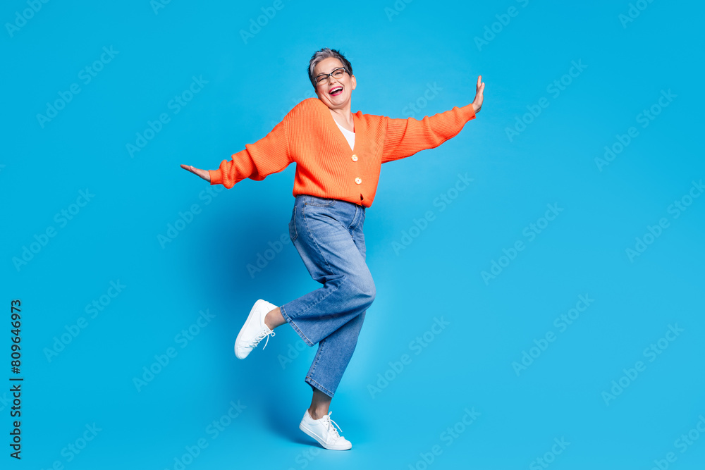 Full body photo of lovely senior lady dancing have fun dressed stylish orange garment isolated on blue color background