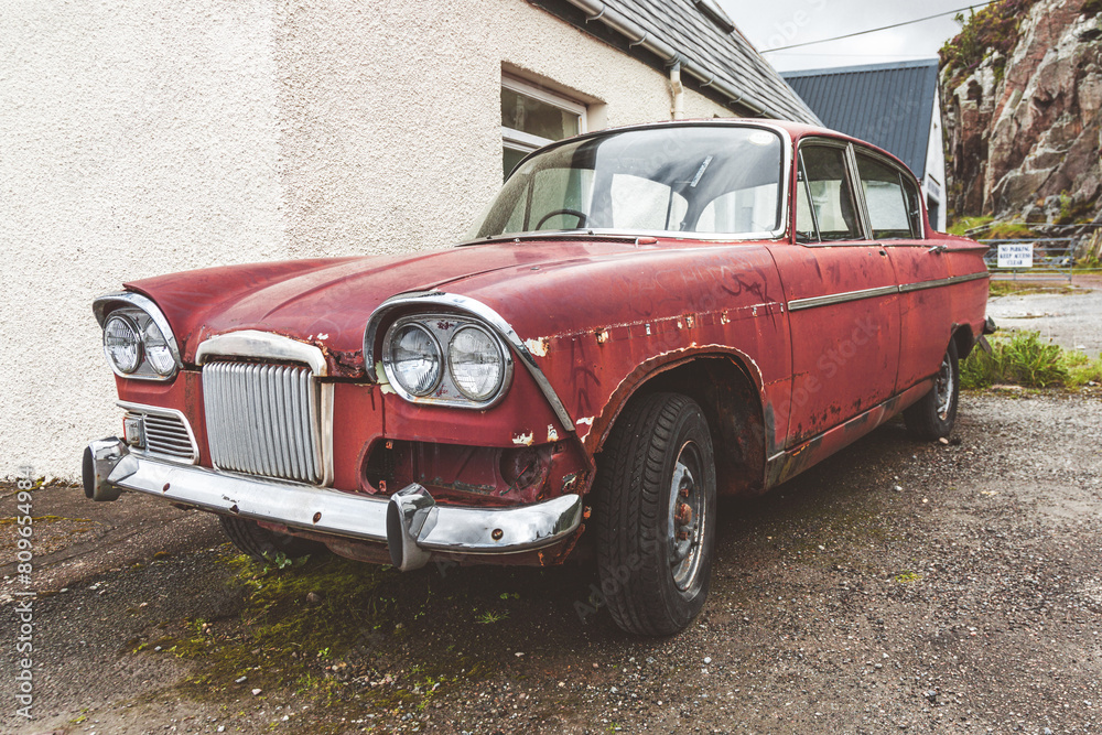 Old maroon car abandoned next to a house. Old maroon car abandoned next to a house.
