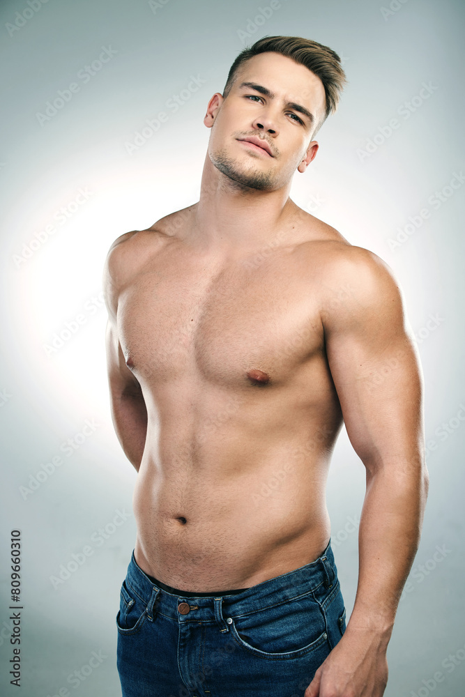 Portrait of man, abs and shirtless in studio with jeans for confidence, physical training or workout results on white background. Body, strong and model for bodybuilder, muscles or transformation