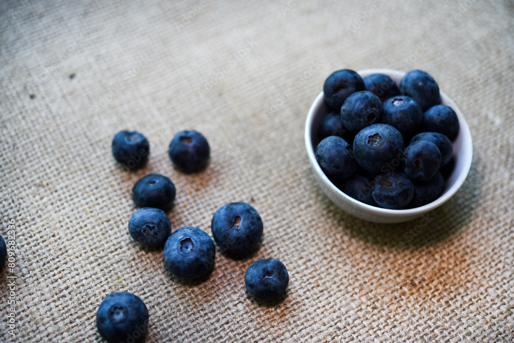 Blueberries in a white bowl on a burlap tablecloth. Juicy blueberries.