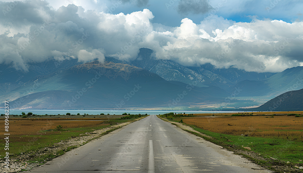 straight asphalt road going into  mountains on he horizon, heavy dark clouds above mountains