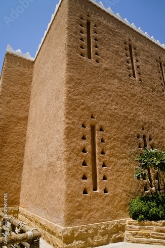 Low angle view on ancient clay walls of arabic tower in heritage village under clear sky photo