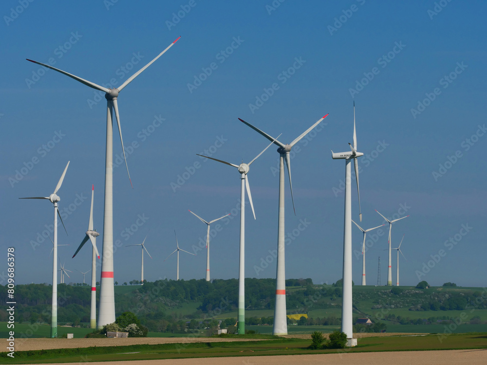 Wind turbines in a wind farm, yellow rapeseed fields,
sustainable energy, energy transition Wind turbines in a wind farm, yellow rapeseed fields,
sustainable energy, energy transition