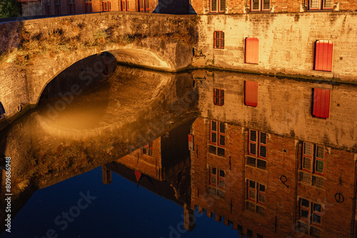 Blinde-Ezelbrug bridge and the historic buildings reflected on the canal in the old town of the beautiful city of Bruges in Belgium at night. © JoseLuis