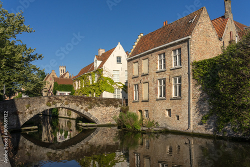 Peerden bridge and historic buildings reflected on the canal in the old town of the beautiful city of Bruges in Belgium in a sunny day. © JoseLuis