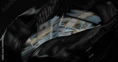 Close-up of a large bag full of money one hundred dollar bills. A bag full of packs of one hundred dollar bills stands on a black background. The concept of wealth, a lot of money.