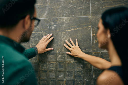 A couple searching for the right ceramic tile for their bathroom, touching one with their hands. photo