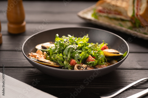 Fresh salad plate with shrimp and arugula on wooden table background. Healthy food