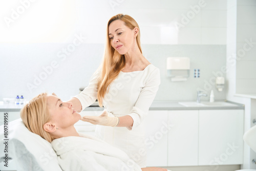 Cosmetician looking at client face after bio revitalization procedure