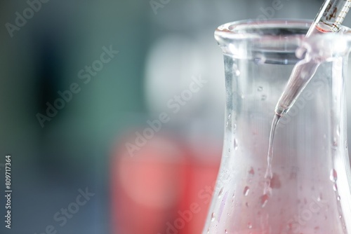 Photos Close-up of a chemistry experiment with a pipette and a beaker of liquid