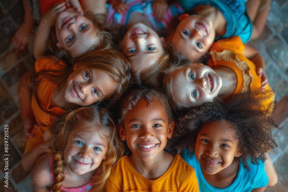 Overhead view of a multicultural group of children in colorful clothing smiling happily in a circle formation