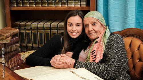 Obraz na płótnie Foto scattata ad una nonna con sua nipote mentre leggono una raccolta di libri antichi. w salonie