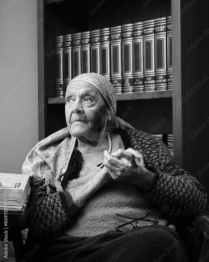 Foto scattata ad una nonna con a fianco una raccolta di libri antichi.