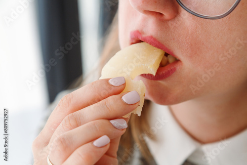 Close-up of a woman's mouth eating dried pineapple, a healthy snack for students.