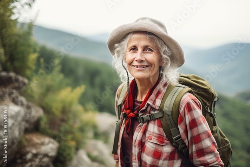 Joyful elderly female hiker with backpack exploring nature in the mountains © juliars