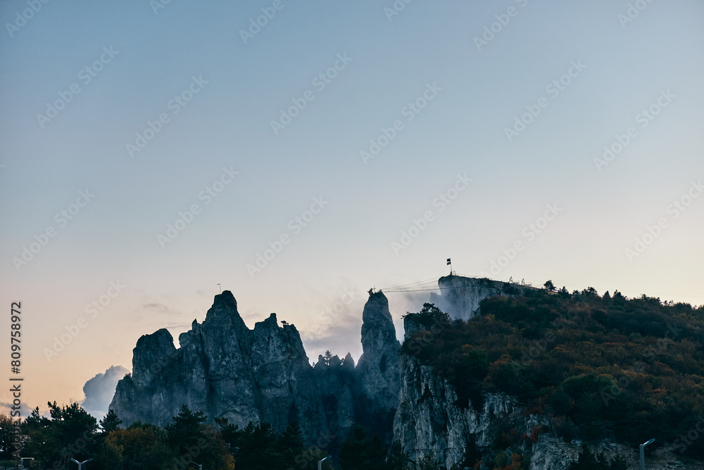 Serenity in Nature Majestic Mountain Sunset with Cross and Trees Silhouetted in the Evening Glow