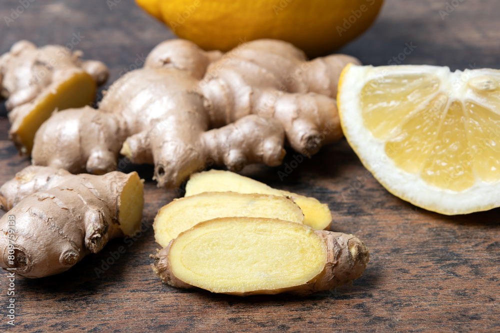 Ginger and lemon on wooden table, focus on slices close up