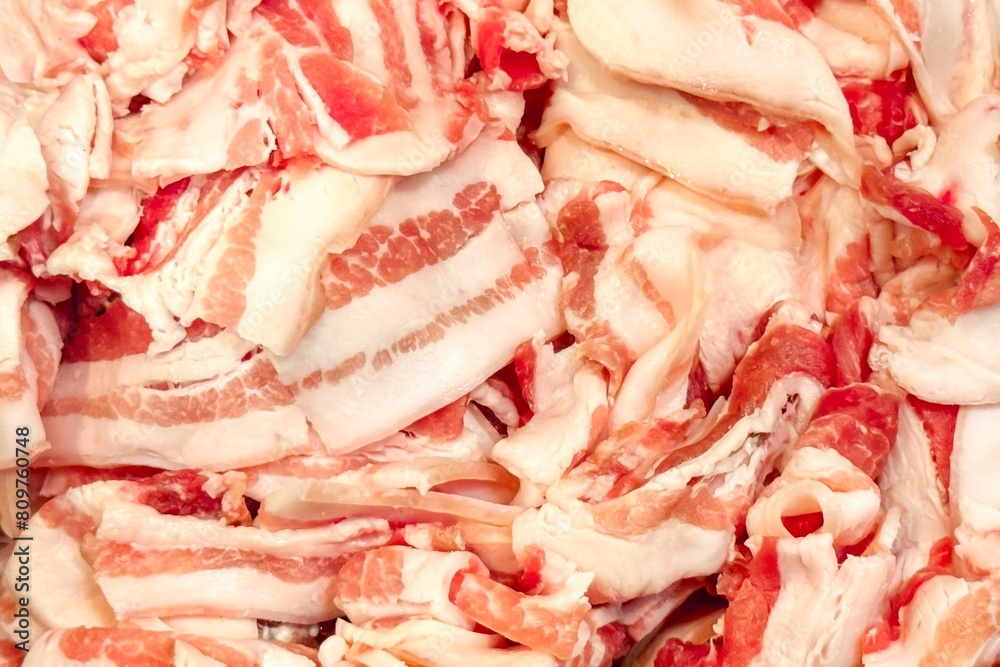 Backdrop of thinly sliced bacon strips arranged in heap, showcasing intricate marbling of fat and meat. Vibrant pink and white layers highlight freshness and rich flavor of bacon