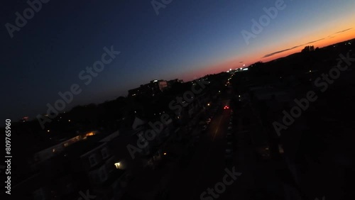 American city at night. Aerial drone FPV shot over street with car driving during sunset, dusk. photo