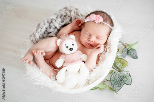 portrait of a sleeping newborn baby girl at home in a crib with a soft pink toy, the child is sleeping sweetly