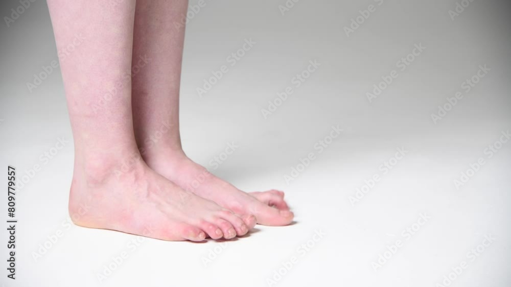 Close-up side view of barefoot caucasian woman standing on white floor and training her dance moves. Soft focus. Real time handheld video. Hobby, leisure and body care theme. Close-up side view of barefoot caucasian woman standing on white floor and training her dance moves. Soft focus. Real time handheld video. Hobby, leisure and body care theme.