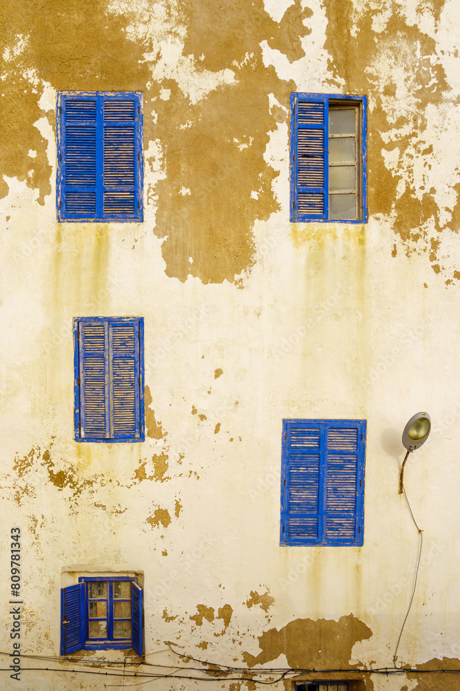 Blue windows and shutters on an old house white wall