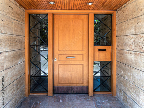 A contemporary design house entrance with a wood and glass door between stonewalls.Travel to Athens, Greece.
