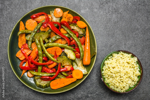 Asian food on plate. Stir fry vegetables on plate and rice in a bowl, top view.