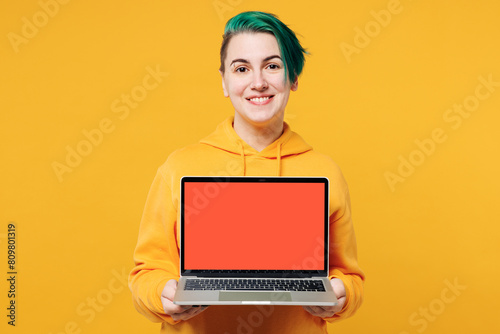 Young happy IT woman with dyed green hair wear hoody casual clothes hold use work on blank screen workspace area laptop pc computer isolated on plain yellow orange background studio Lifestyle concept
