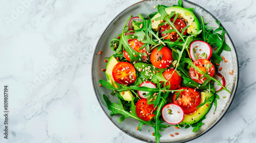 Fresh raw vegetables on a plate, a close-up view of an avocado salad, tomato and arugula from above.