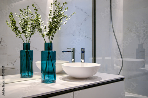 Blue decorative vase and its reflection in the mirror of a modern style bathroom with a lot of marble and glass.