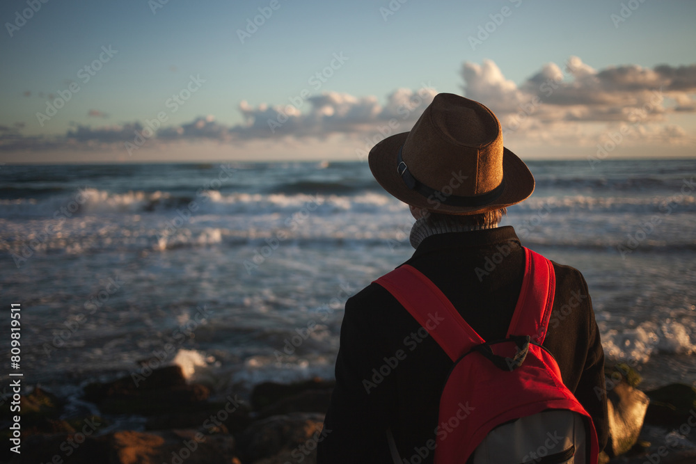 Gentle breeze accompanies man's seaside stroll at dusk.