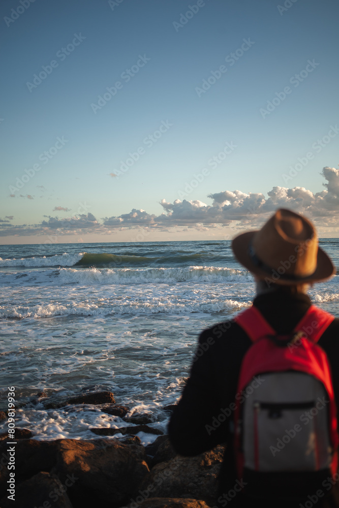 Fototapeta premium Silhouetted figure strolls serene shoreline at twilight.