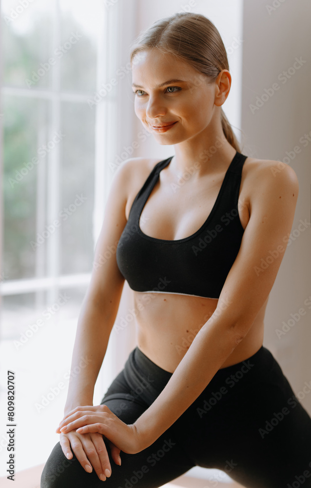 Profile portrait of young attractive yogi woman breathing fresh air, her eyes closed, meditation pose, relaxation exercise, working out wearing black sportswear top, close up image, window background Profile portrait of young attractive yogi woman breathing fresh air, her eyes closed, meditation pose, relaxation exercise, working out wearing black sportswear top, close up image, window background