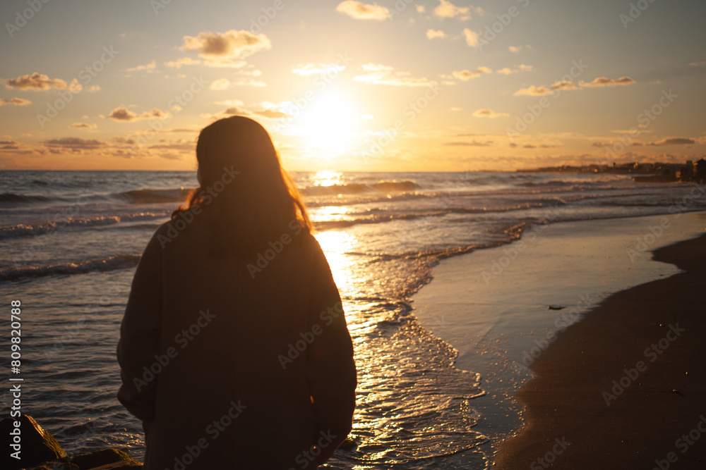 Sunset beach walk for serene woman.