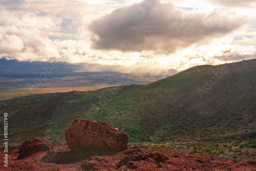 clouds over the green volcano mountains at sunset time from view point of Mauna Kea national park with lava rock in front from the top view at Big Island Hawaii USA