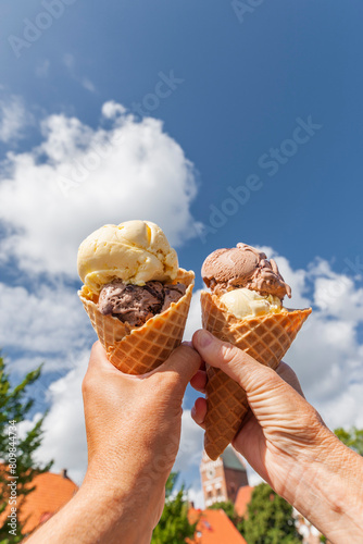 Eistüte mit Eiskugeln in der Hand vor blauem Himmel photo