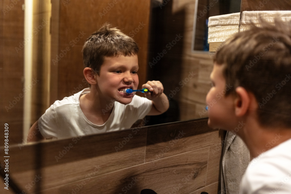 Shot of a little boy brushing his teeth in a bathroom at home. Shot of a cheerful young boy looking at his reflection in a mirror while brushing his teeth in the bathroom at home.