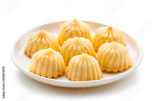 a plate of small yellow desserts on a white surface