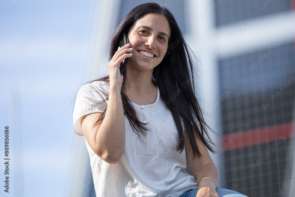 Woman on vacation in the city talking on her mobile phone. Happy and smiling woman talking on her cell phone. Girl sitting talking on her cell phone in the city. Woman on vacation in the city talking on her mobile phone. Happy and smiling woman talking on her cell phone. Girl sitting talking on her cell phone in the city.
