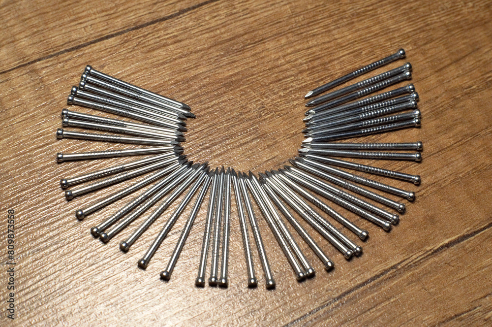 Galvanized nails and fasteners lie on a wooden floor