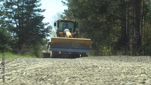 Repair of the road in the middle of the forest with the help of a grader
